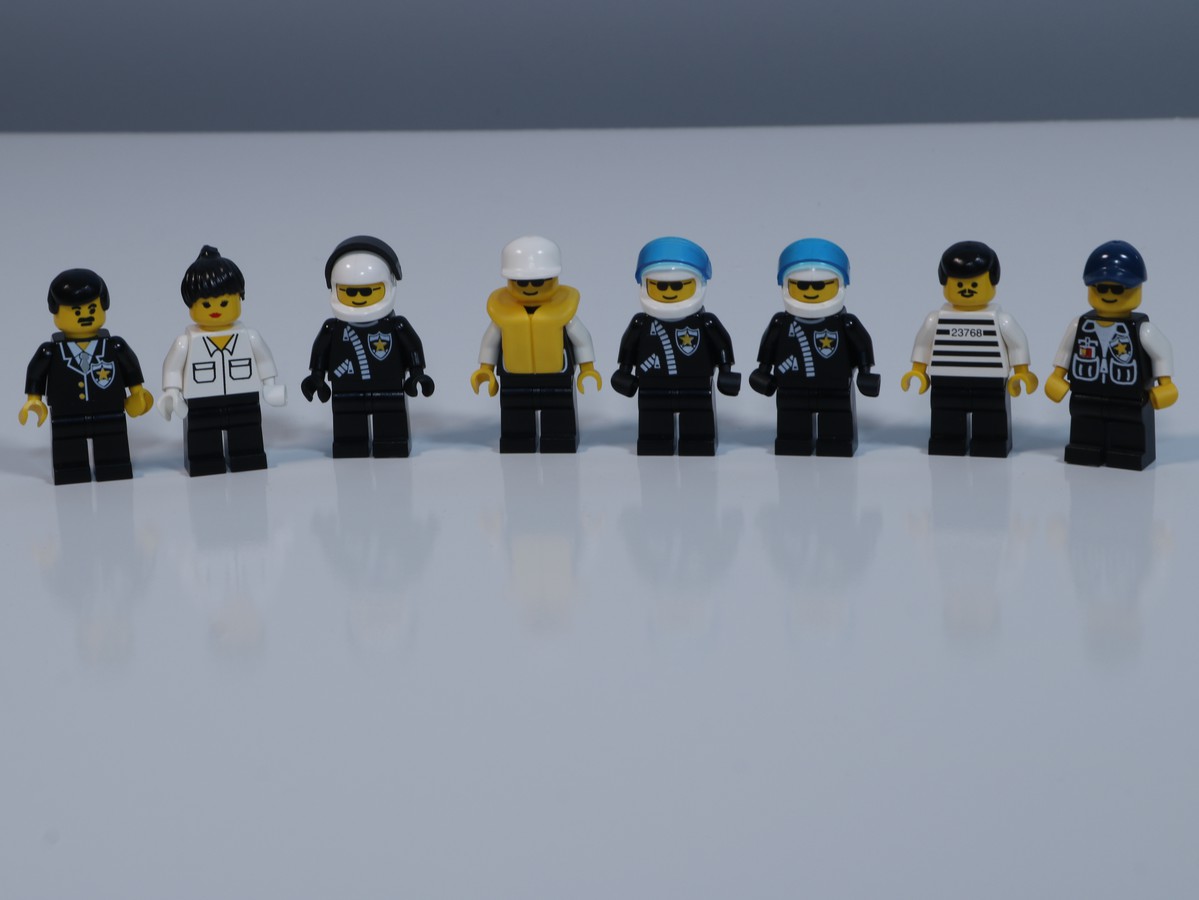 An image of the minifigures form the LEGO Police Station set (6598) The scene includes 5 police officers, two office workers, and a convict. 