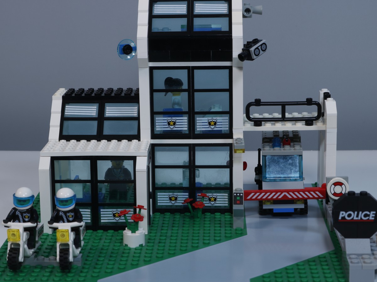 A close-up image of the LEGO Police Station (set 6598), showing details of the police station building. The structure features a classic design with a black and white color scheme and large windows. 