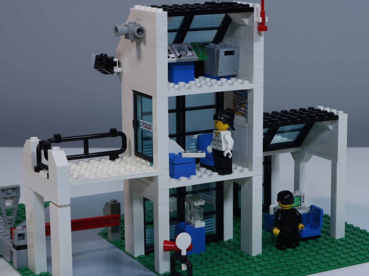 A close-up image of the back rooms of the LEGO Police Station (set 6598), The scene includes a office space with a desk, computer, and police equipment. Accessories such as a map of the city are hung on the walls. 