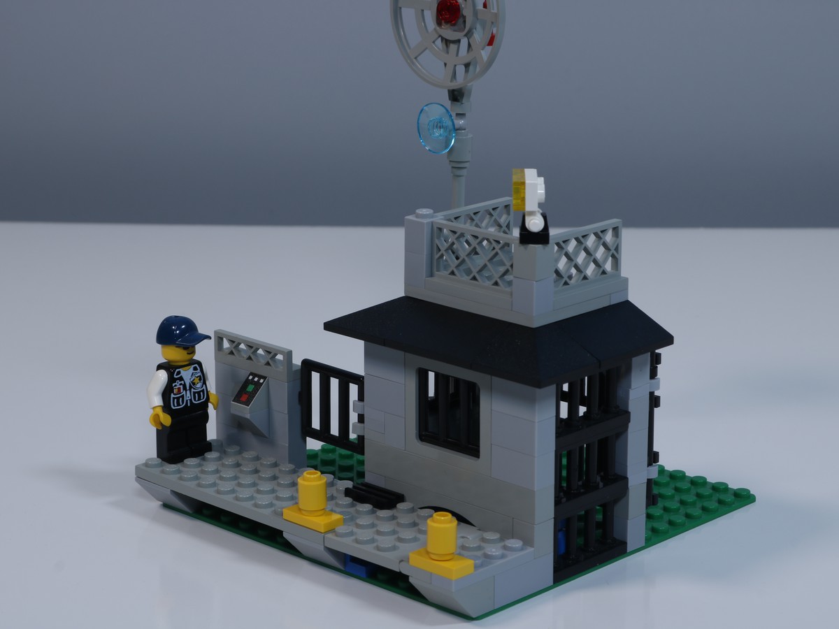 A image of the back of the jail cell from the LEGO Police Station (set 6598), featuring a minifigure police officer standing guard. 