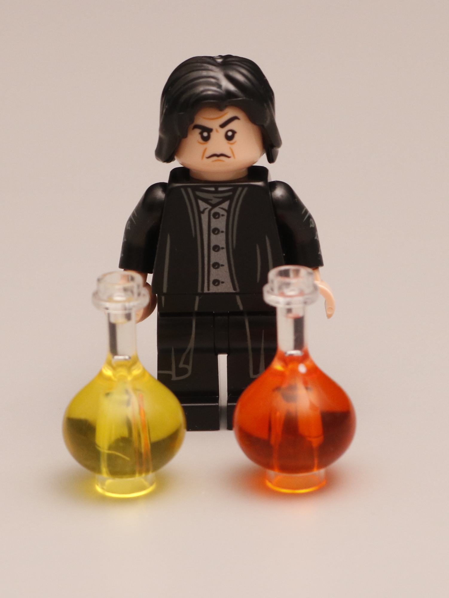 Snape minifiure standing behind large potion bottles.